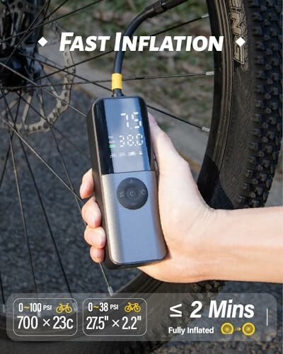 Hand holding a portable bike pump inflating a bicycle tire.